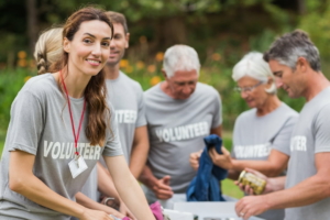 Group of volunteers smiling around boxes with benefits of voluntary workers insurance